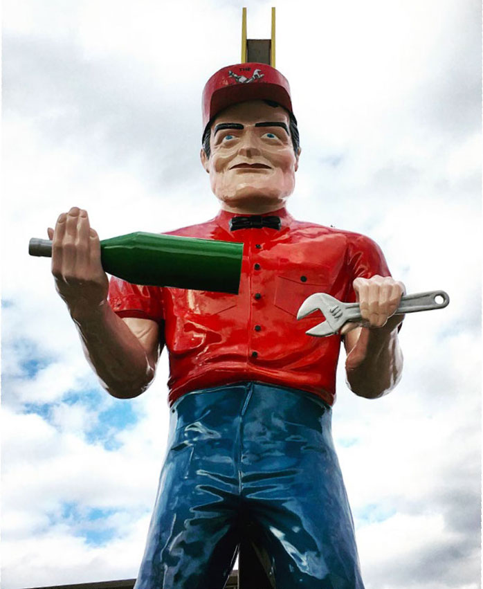 A roadside giant holding a bottle and a wrench